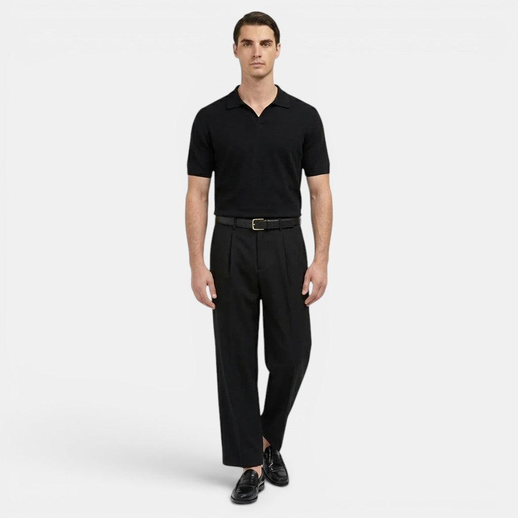 Man wearing a black polo shirt and black pants on a white background