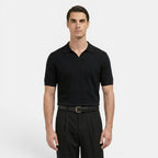 Man wearing a black polo shirt and black pants on a white background