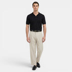 Man wearing a black polo shirt and beige pants on a white background