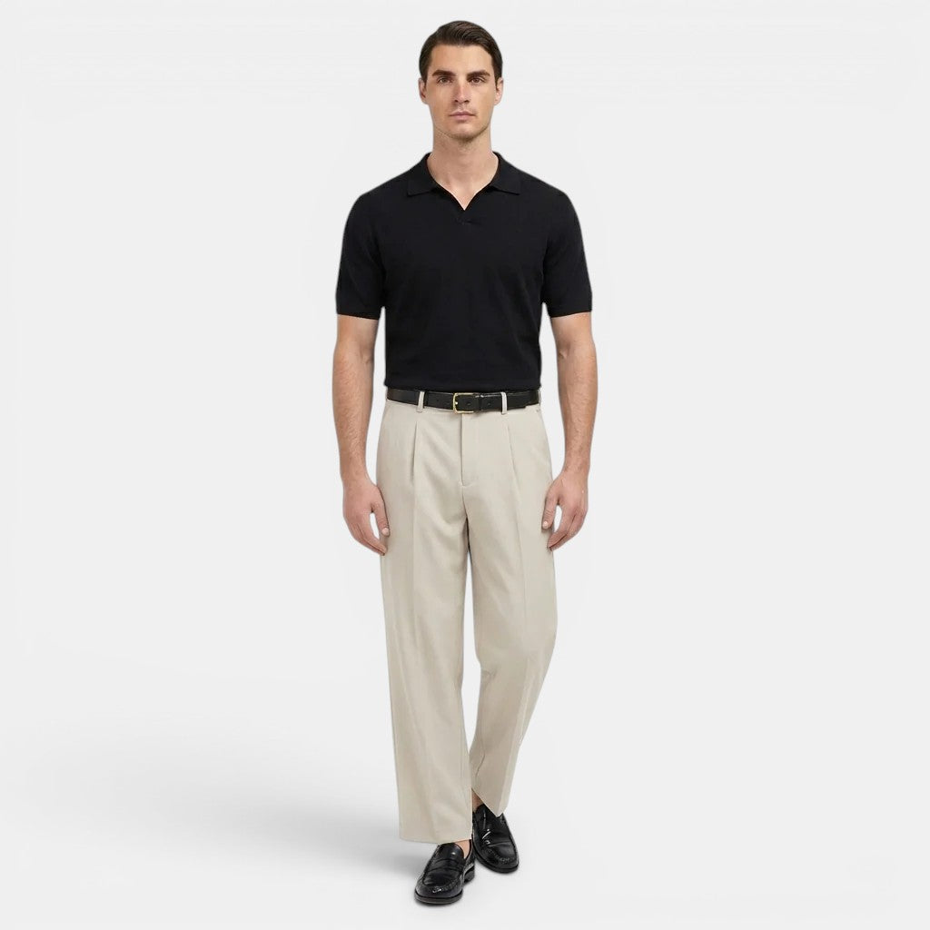 Man wearing a black polo shirt and beige pants on a white background