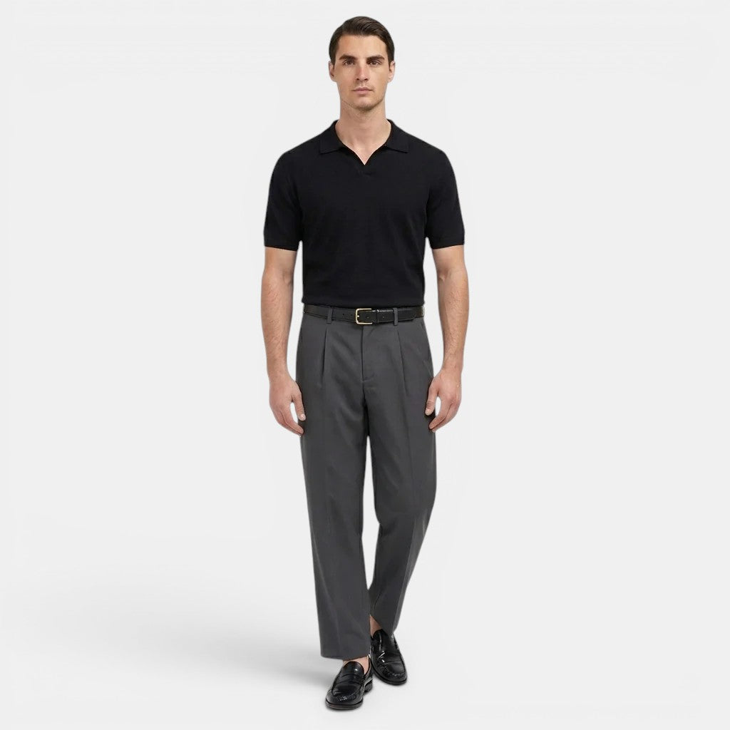 Man wearing a black polo shirt and gray pants on a white background