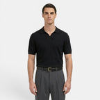 Man wearing a black polo shirt and gray pants on a white background