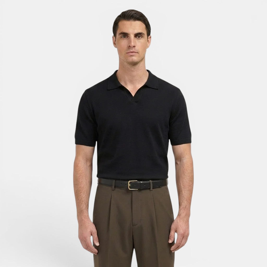 Man wearing a black polo shirt and brown pants on a white background