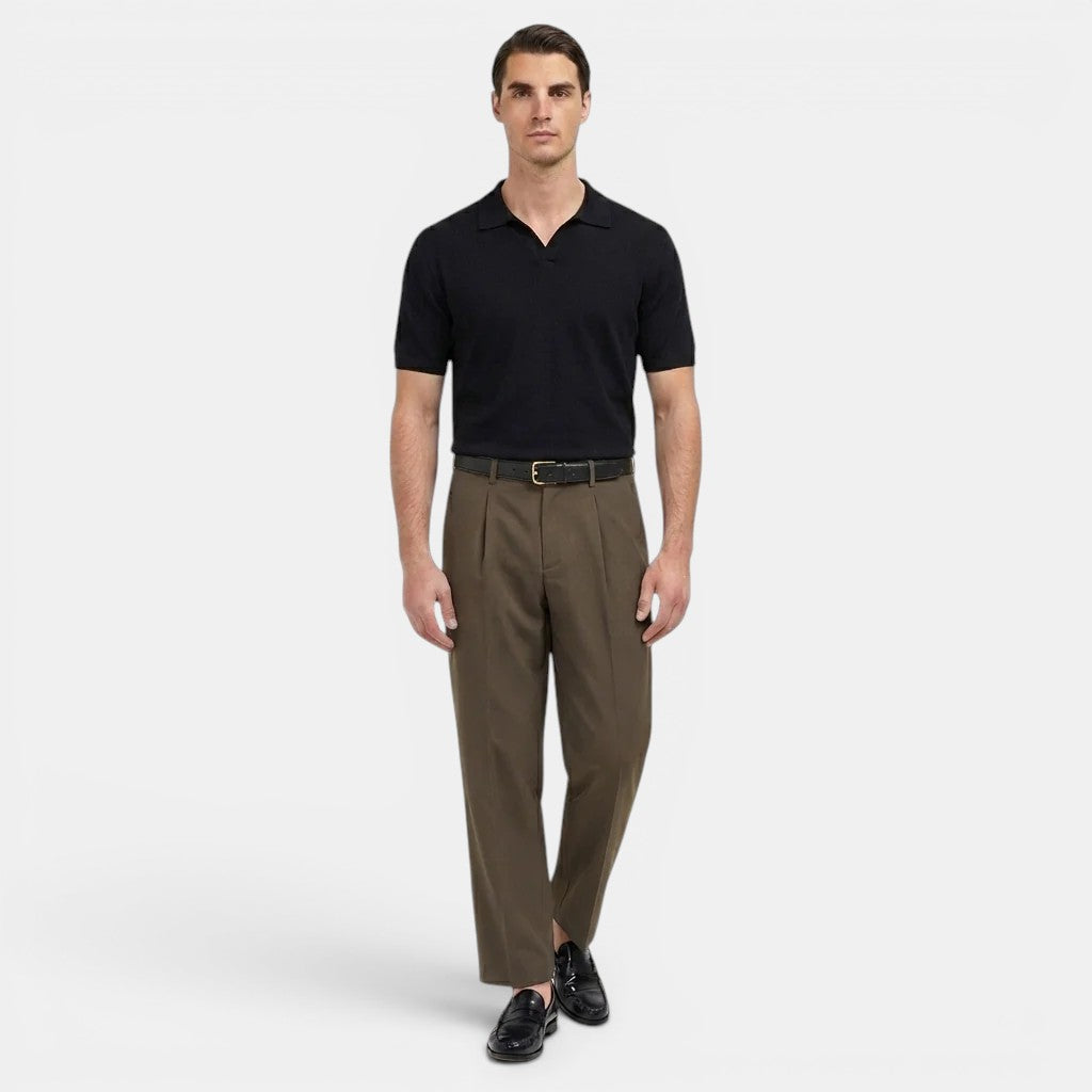 Man wearing a black polo shirt and brown pants on a white background
