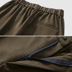 Brown pants with an elastic waistband and a zipper detail on a light gray background