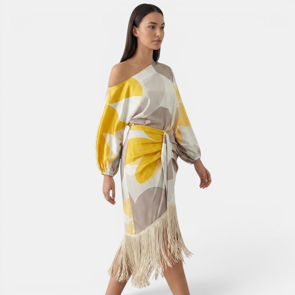 Woman wearing a yellow and beige patterned dress with fringe on a white background