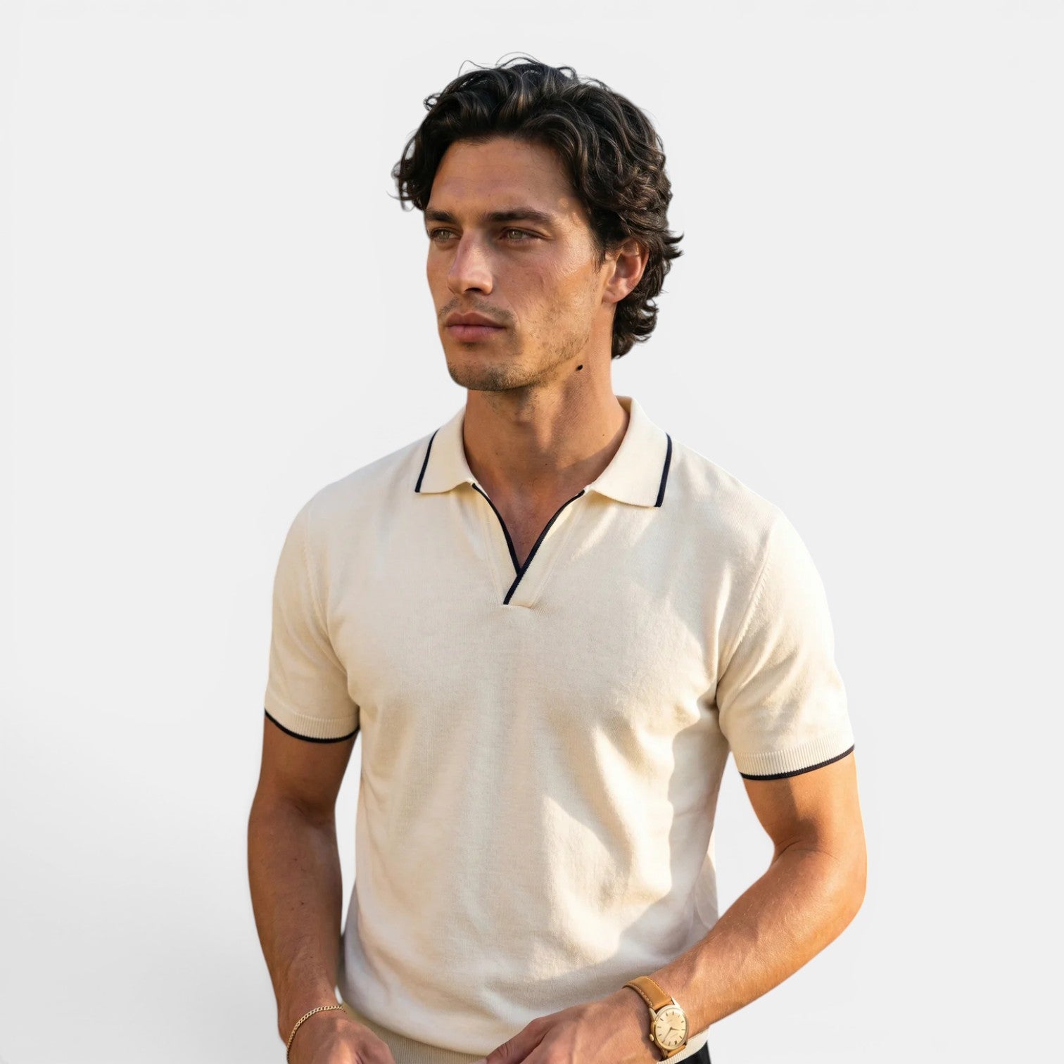 Man wearing a beige polo shirt with black trim on a light background