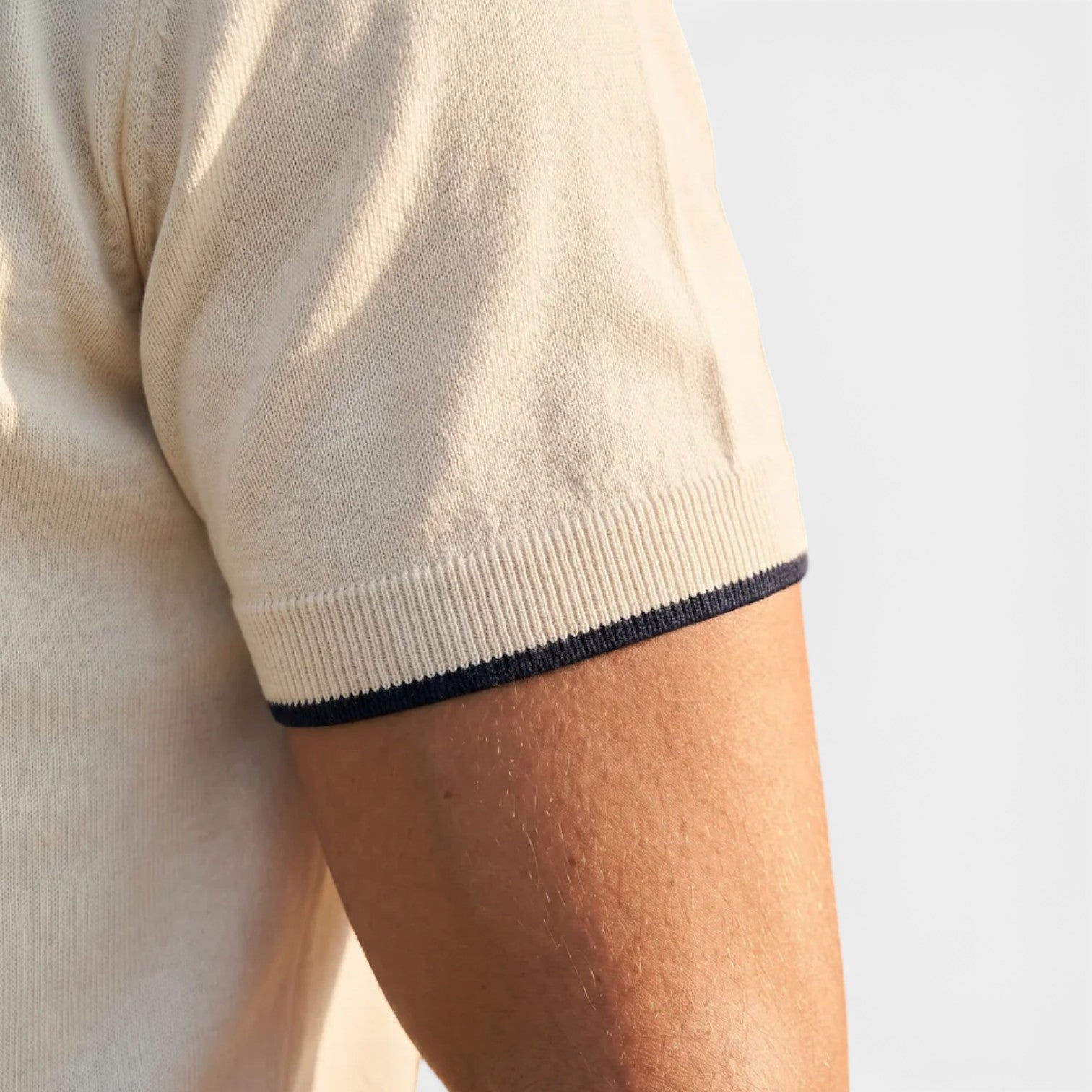 Close-up of a person wearing a beige sweater with a white background