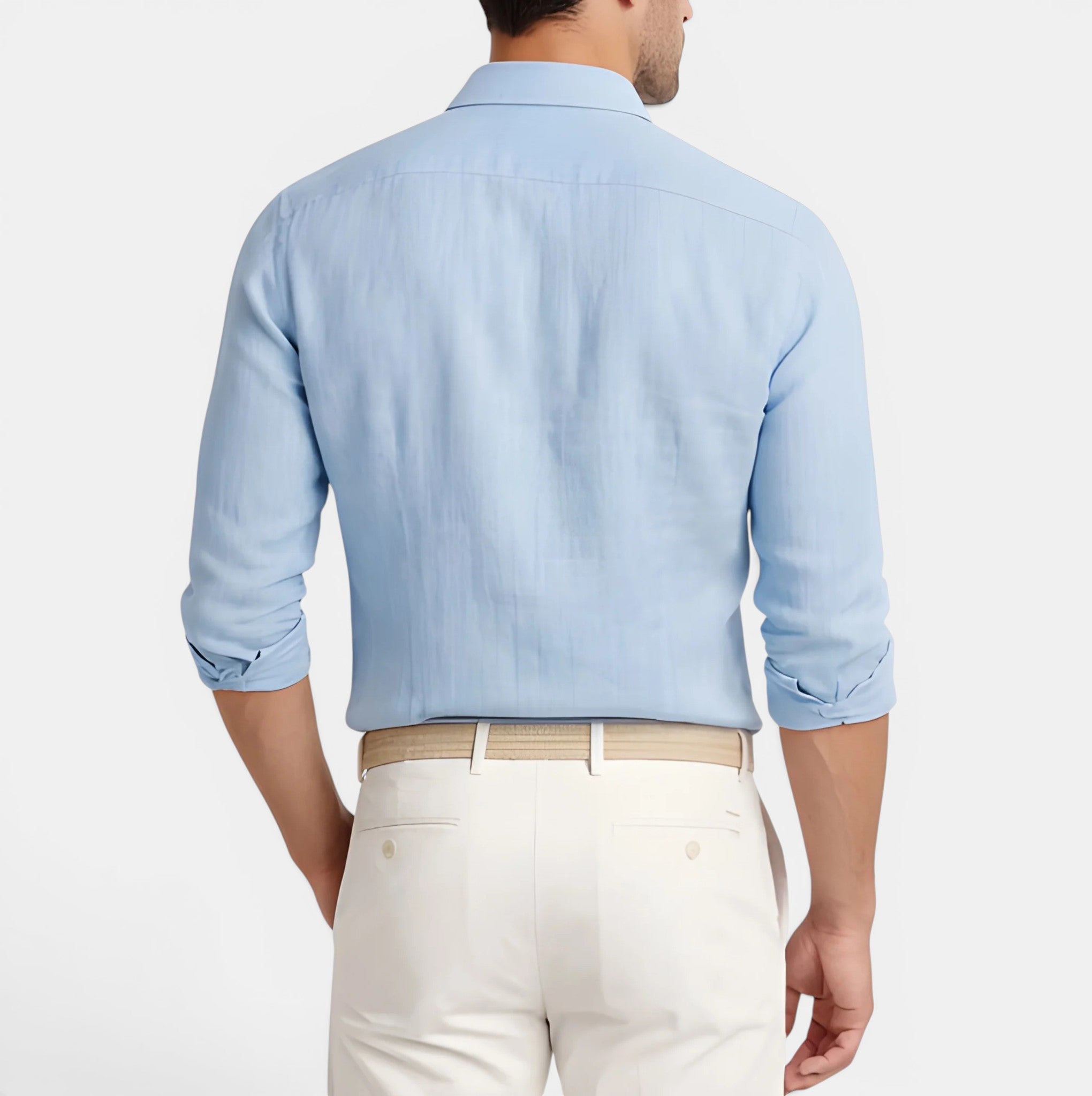 Man wearing a light blue shirt and white pants on a plain background