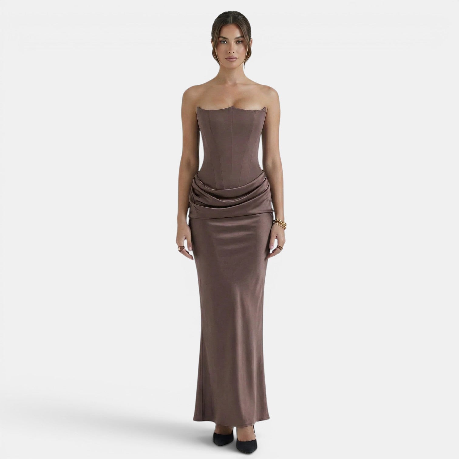 Woman wearing a strapless mocha maxi dress with a fitted corset bodice and draped waist detail.