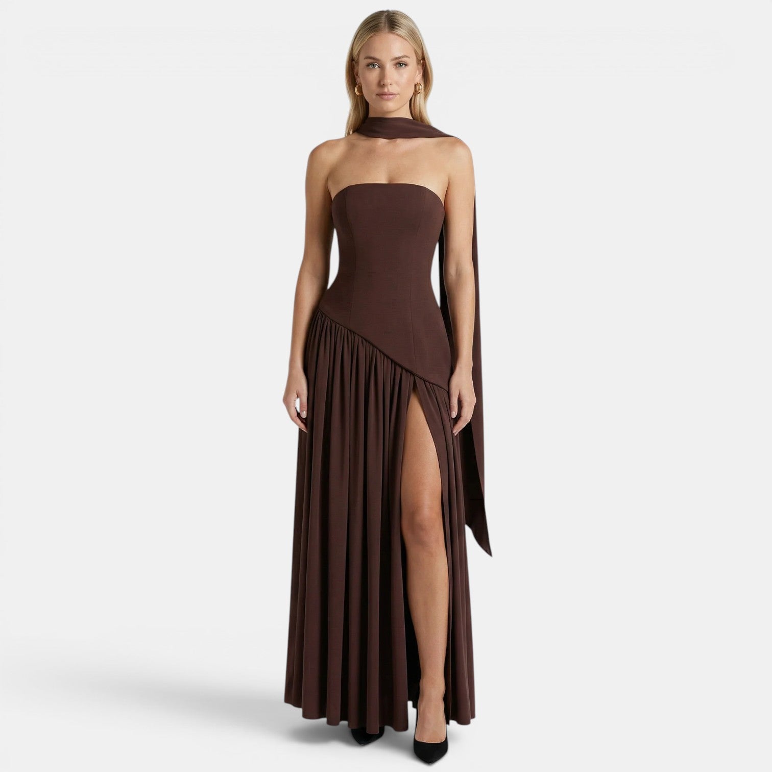 Woman wearing a dark brown strapless maxi dress with a scarf neckline and thigh-high slit, standing against a light gray background.