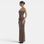Side view of a woman wearing a strapless mocha maxi dress with a fitted corset bodice.