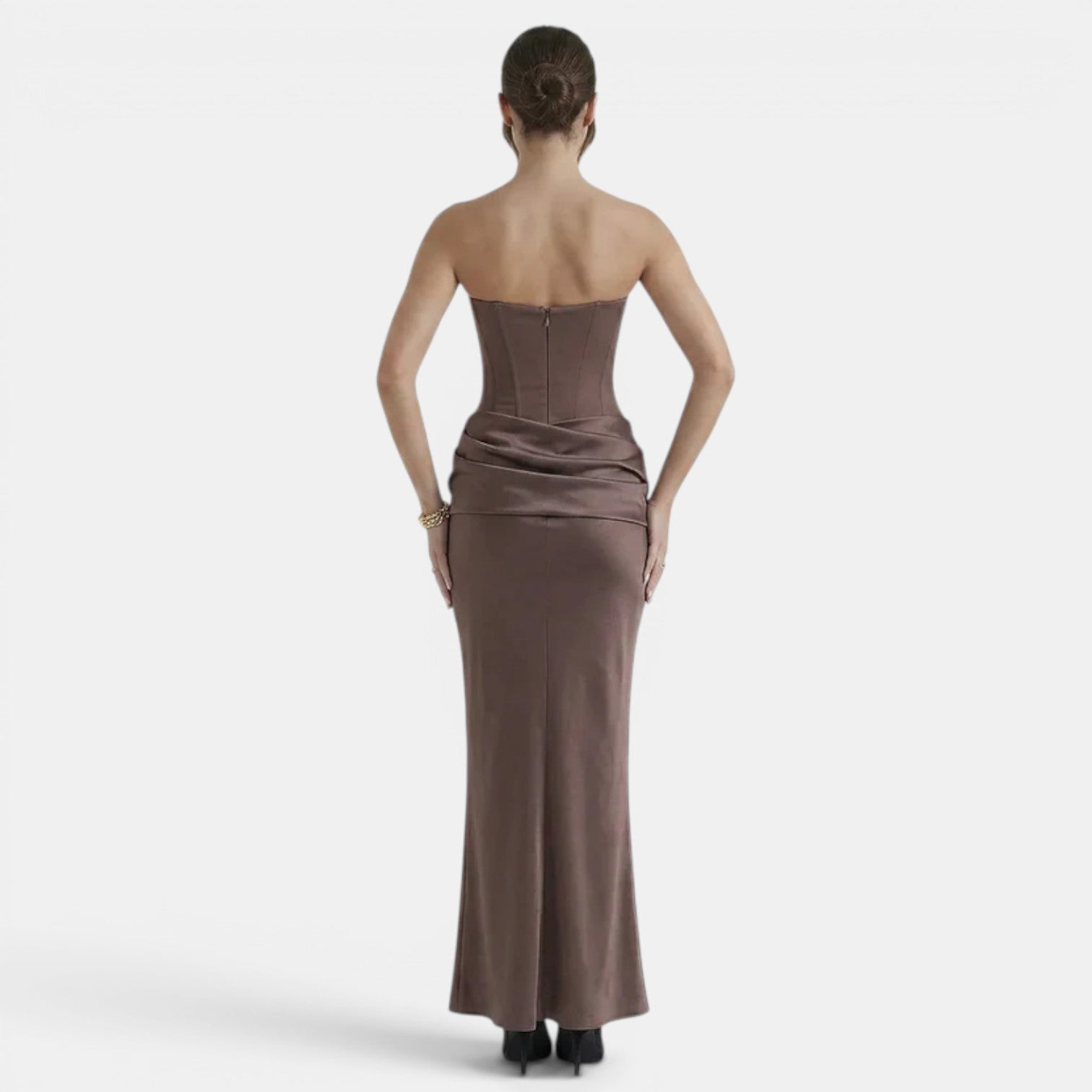 Back view of a woman wearing a strapless mocha maxi dress with a fitted corset bodice and draped waist.