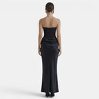 Back view of a woman wearing a strapless navy maxi dress with a fitted corset bodice.