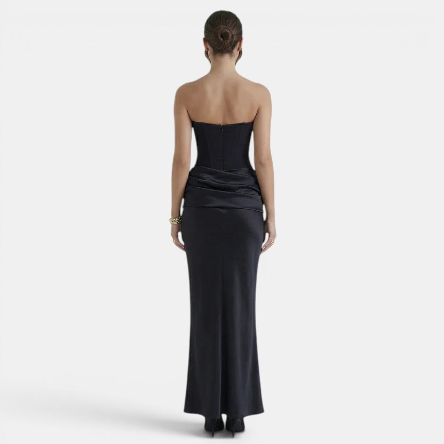 Back view of a woman wearing a strapless navy maxi dress with a fitted corset bodice.