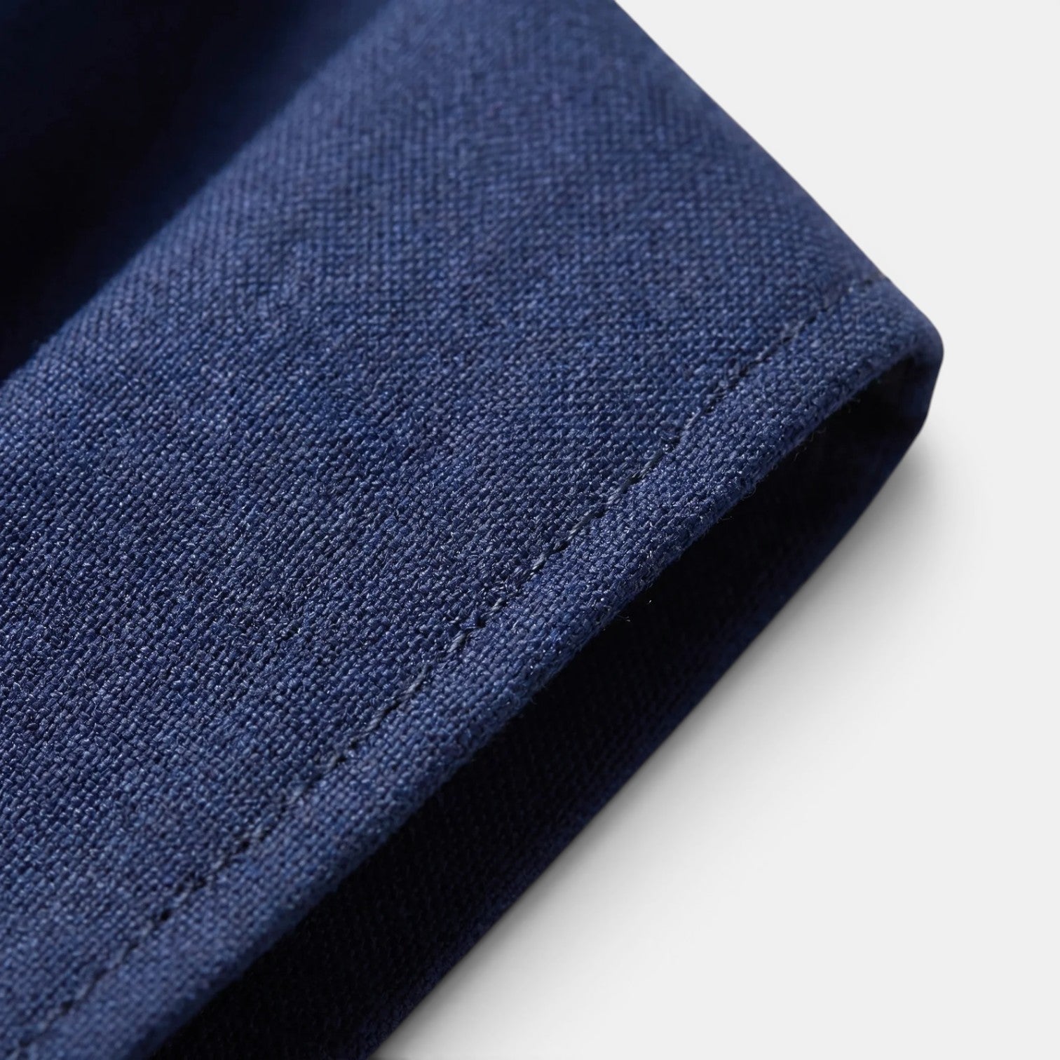 Close-up of navy blue suit fabric showcasing fine texture and tailored stitching detail.
