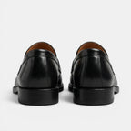 Black leather loafers on a light gray background