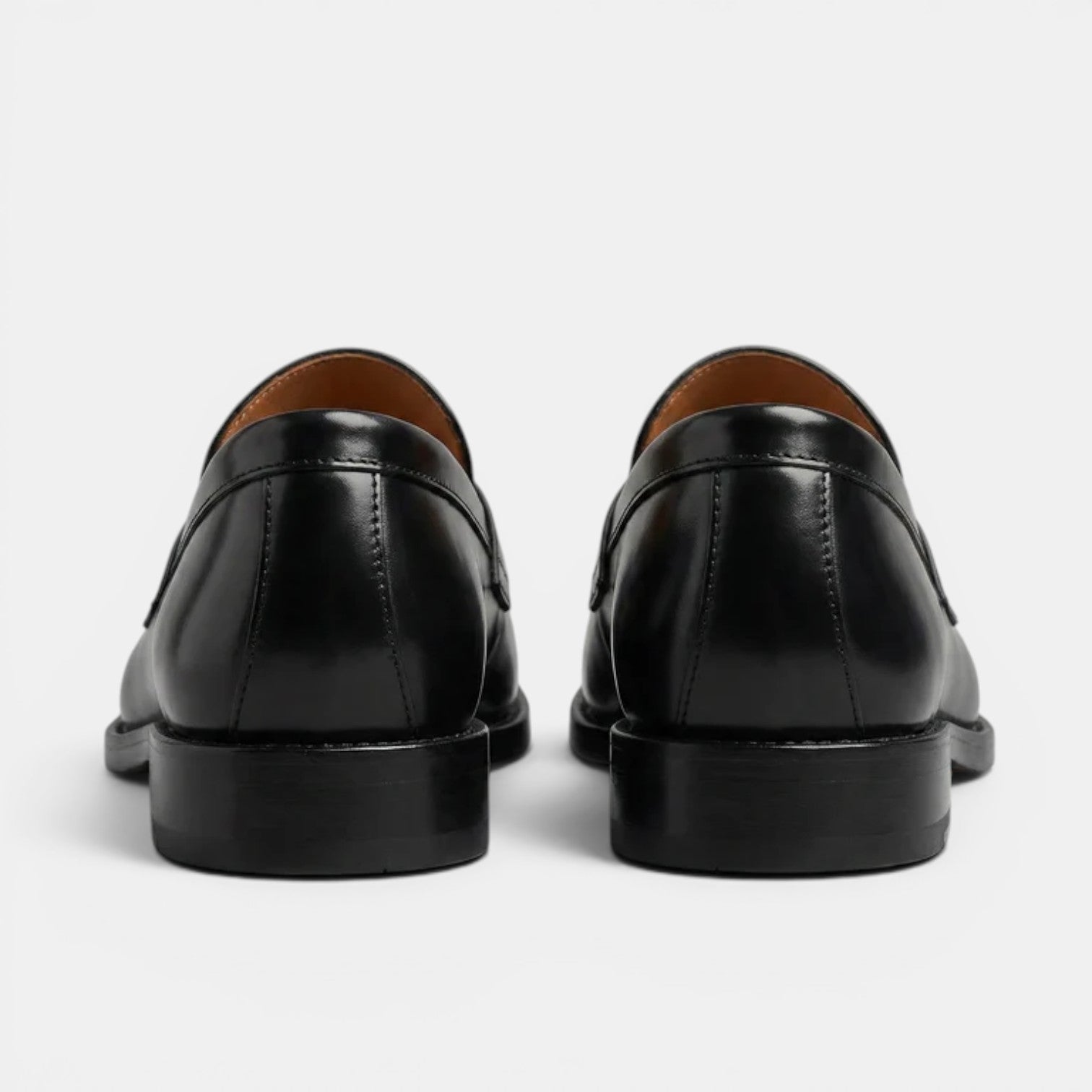 Black leather loafers on a light gray background