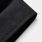 Close-up of black suit fabric showcasing fine texture and tailored stitching detail.