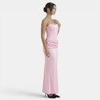 Side view of a woman wearing a strapless blush pink maxi dress with a fitted corset bodice.