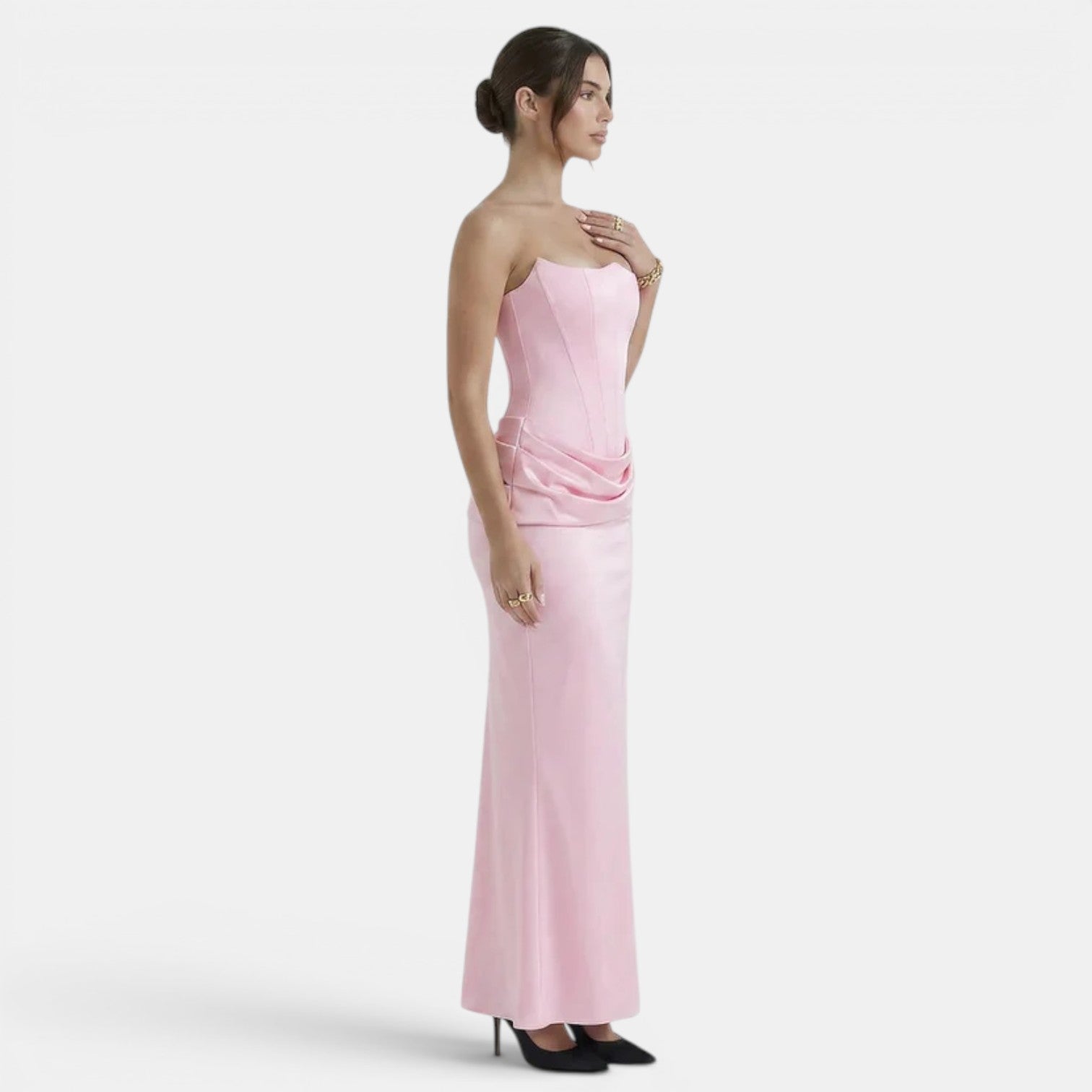 Side view of a woman wearing a strapless blush pink maxi dress with a fitted corset bodice.