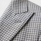 Close-up of a gray houndstooth blazer showcasing textured fabric and tailored lapel detail.