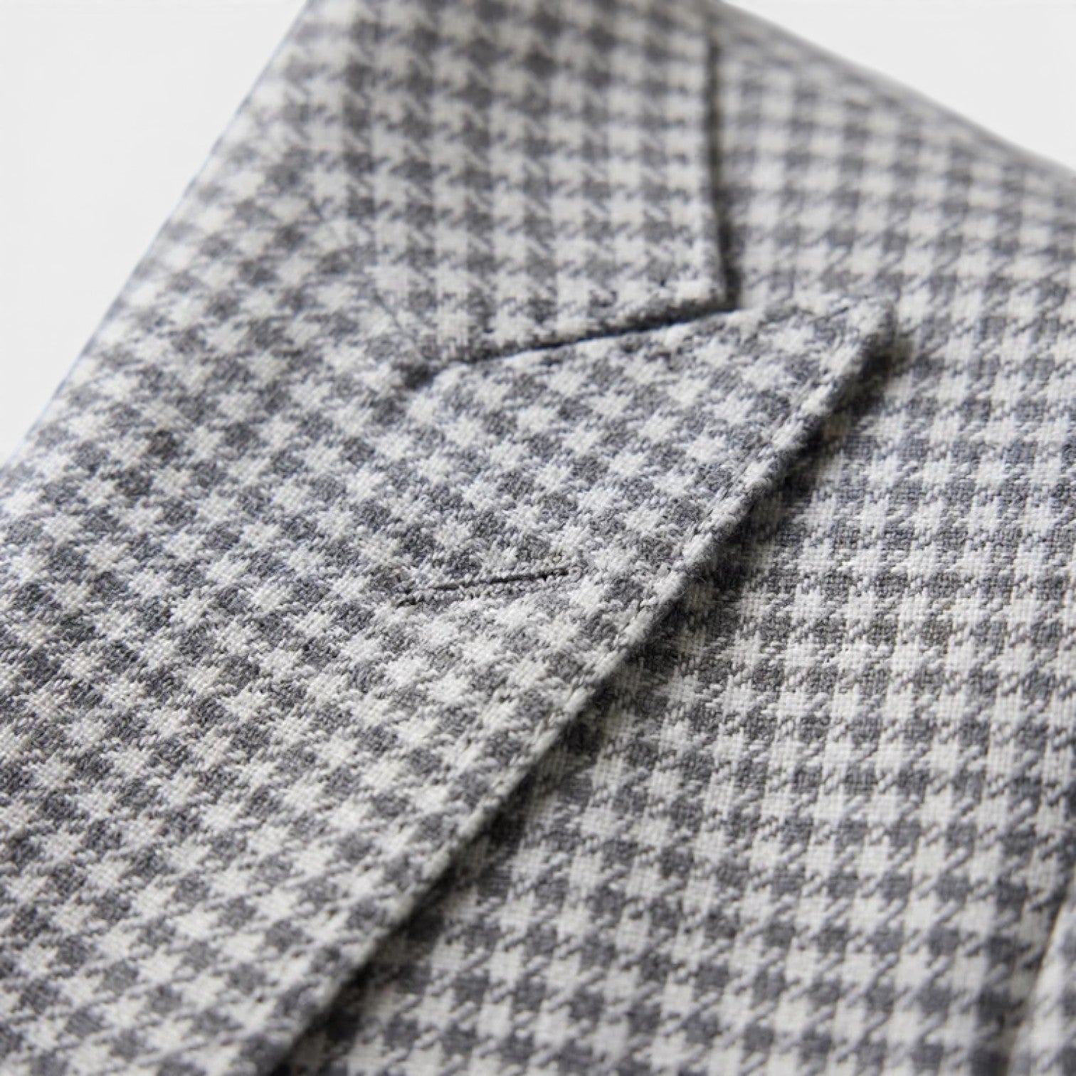 Close-up of a gray houndstooth blazer showcasing textured fabric and tailored lapel detail.
