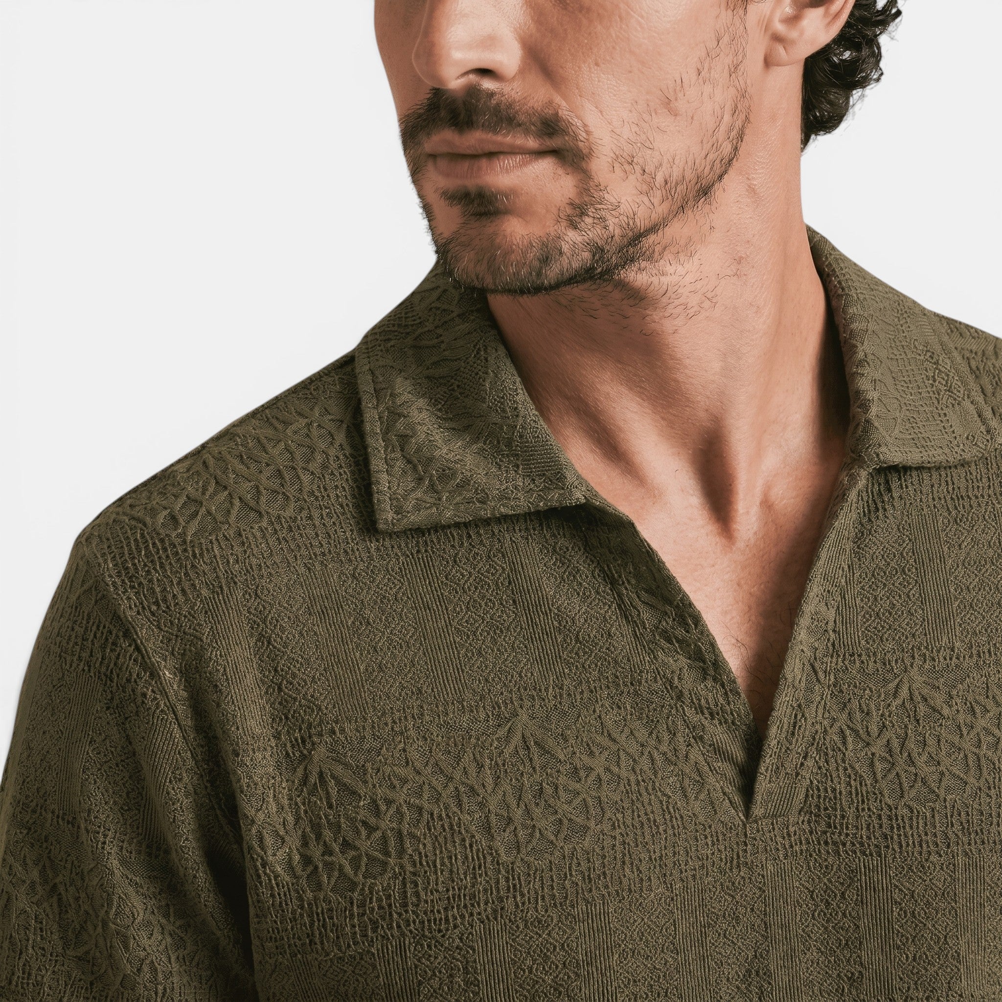 Close-up of an olive green textured knit polo shirt with an open collar, highlighting the fabric pattern and neckline.