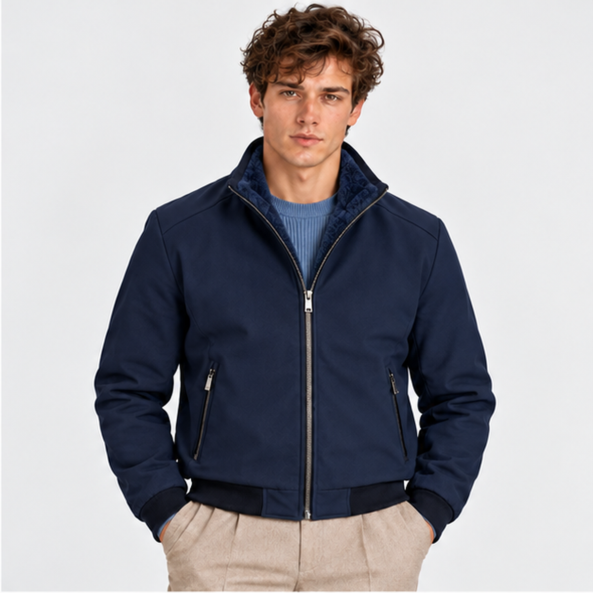 Men's black zip-up bomber jacket styled with a blue shirt and beige trousers