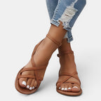 Brown strappy sandals worn with ripped jeans on a white background
