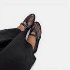 Black mesh sandals worn with black pants on a white background