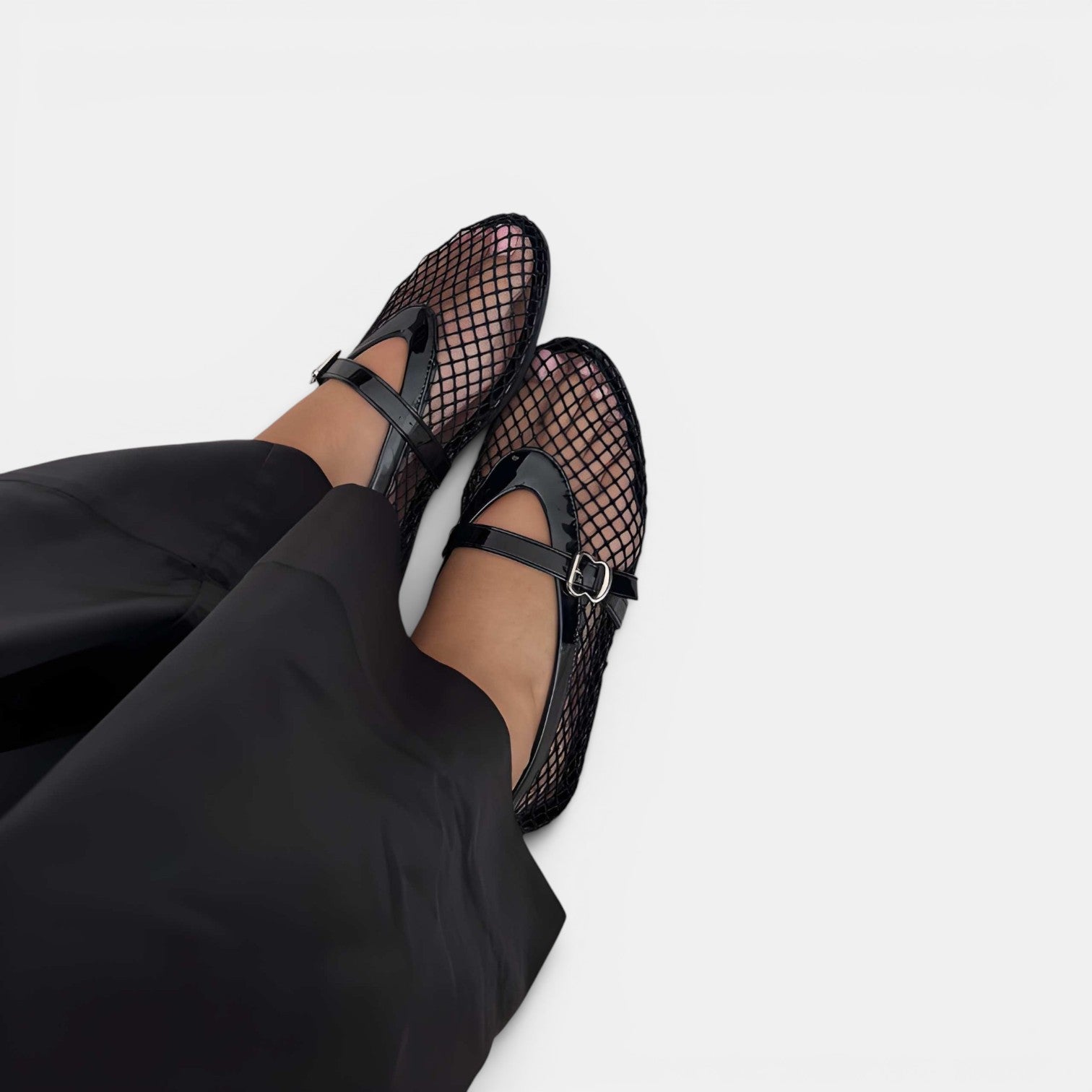 Black mesh sandals worn with black pants on a white background