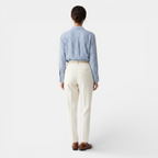 Person wearing a blue striped shirt and white pants on a white background