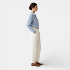 Woman wearing a blue checkered shirt and beige pants on a white background