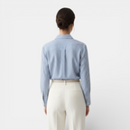 Person wearing a blue striped shirt and white pants on a light gray background
