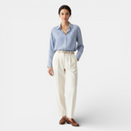 Woman wearing a blue striped shirt and white pants on a white background