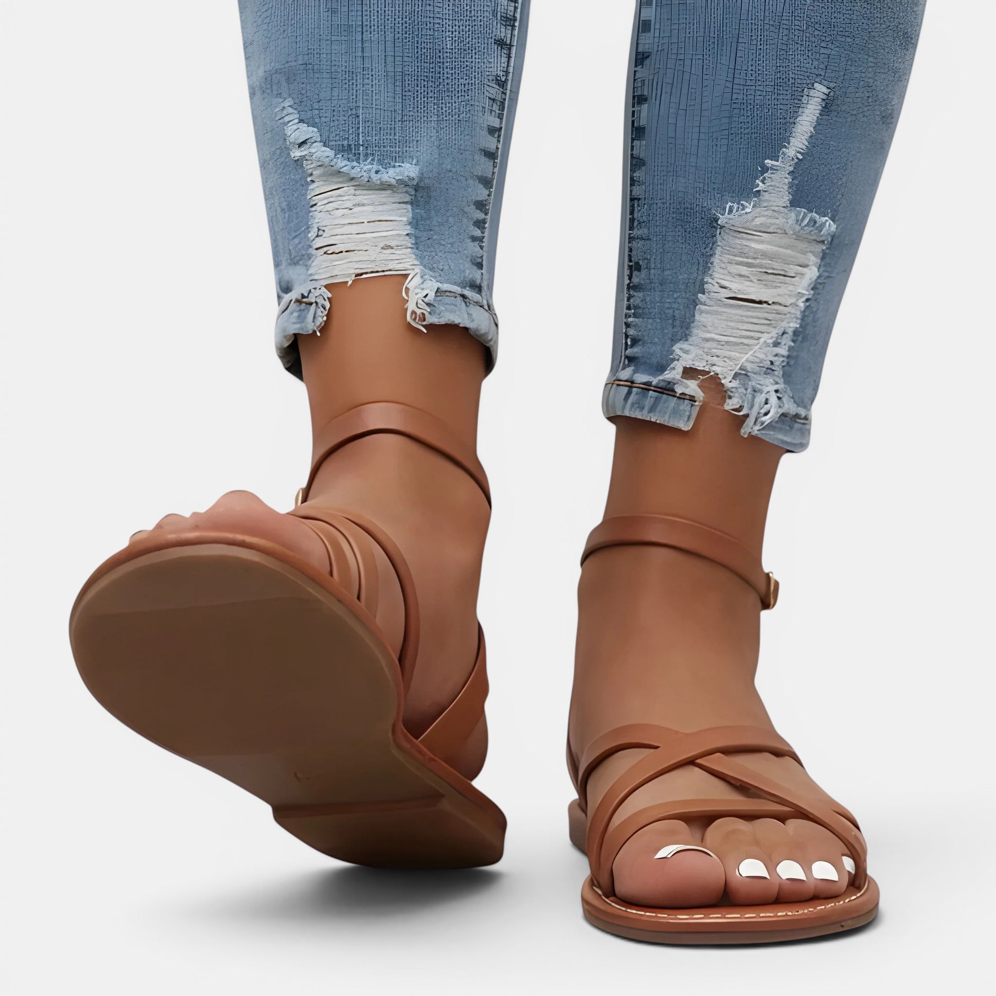 Brown sandals worn with ripped jeans on a white background