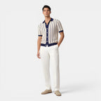 Man wearing a striped shirt and white pants on a plain background